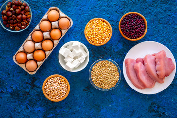 Food for sportsmen. Legumes, nuts, low-fat cheese, meet, eggs on blue table top view