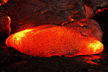 Scenic view of a part of a lava flow in the dark, the hot lava shows up in yellow and red shades -...