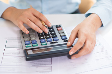 Closeup of female economist counting data on calculator. Person pressing buttons and working....