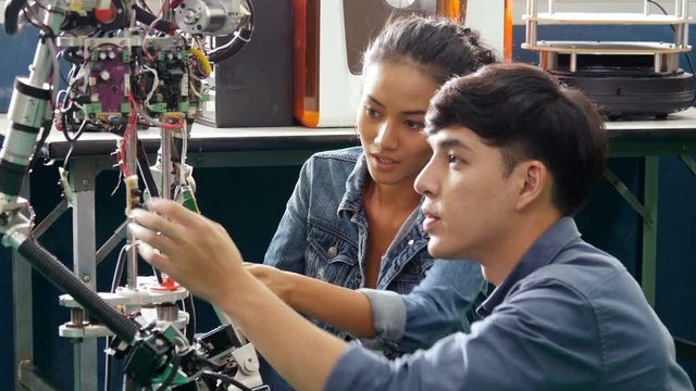 Team engineer collaborating on develop of robotics prototype project in workshop. People with technology or innovation concept. 4K Resolution.