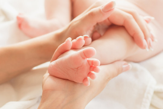 Hands of woman holds baby foot