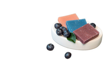 Pieces of natural handmade soap and fresh blueberry on white background.
