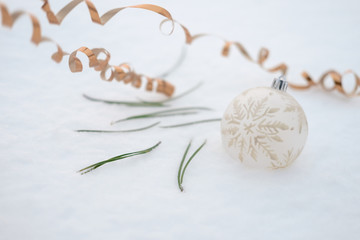Christmas ball, Christmas tree needles, golden serpentine lie on the snow.