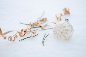 Christmas ball, Christmas tree needles, golden serpentine lie on the snow.