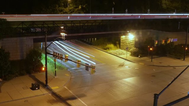 A high angle night time lapse view of traffic passing through an intersection in a large city.  	