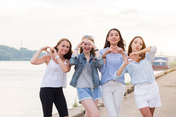 Obraz premium Four Young Women In Studio Standing In Line and show heart gesture together with arms outdoor