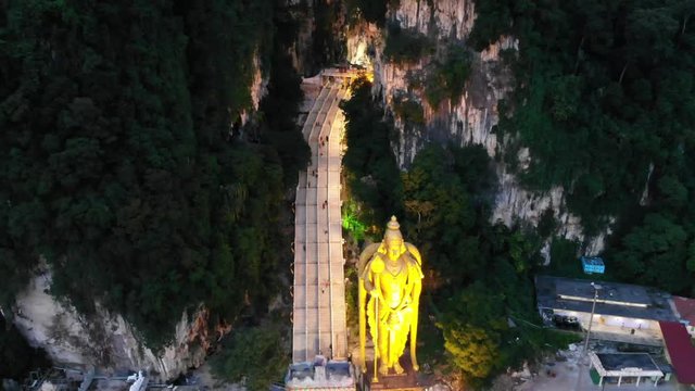 backsweep aerial of murugan statue by batu cave stairs