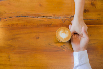 hands of couple drinking coffee at cafe together ,heart shape latte art in coffee cup.