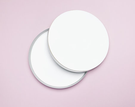 Round white cardboard blank box top view flat lay. Mock up on pink background. Packaging design, an empty box for shopping.