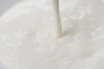 Close-up pouring milk into white bowl with motion blur
