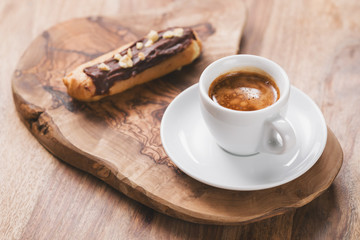 espresso with eclair on wooden board