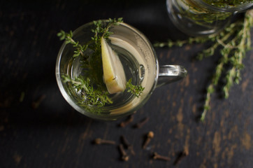 Herb tea with thyme, apple and cloves is on a dark background