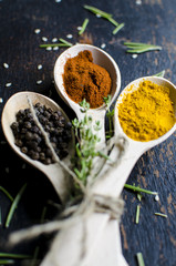 White spoons with spices are on a black wooden table