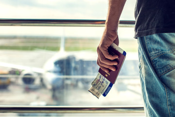 Closeup of man holding passports and boarding pass at airport. Traveling concept - obrazy, fototapety, plakaty