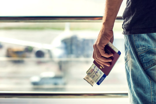 Closeup of man holding passports and boarding pass at airport. Traveling concept