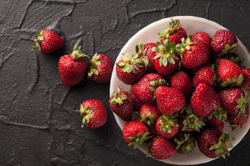 Fresh strawberries in a plate on a black background.