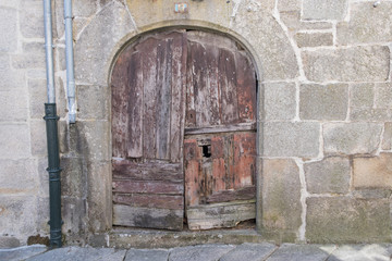 Fototapeta na wymiar Puerta de arco antigua de madera en casa de piedra de estilo medieval