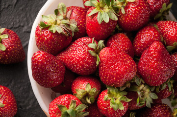 Fresh strawberries in a plate on a black background.