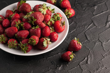 Fresh strawberries in a plate on a black background.