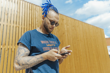 Young man with blue dreadlocks dancing reggaeton in the street.