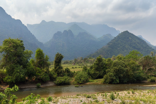 Scenic view of Nam Song River, fields and limestone mountains near Vang Vieng, Vientiane Province, Laos.