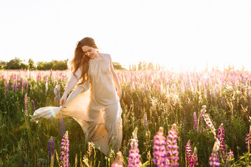 Young woman standing on a wildflower field with sunrise on the background