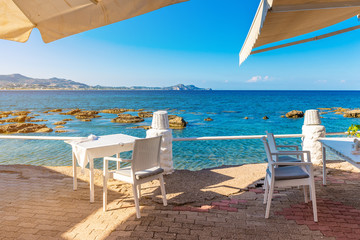 Table and chairs in coastal restaurant on Kolymbia beach. Rhodes island, Greece