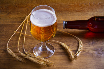 Glass and bottle of beer, ears of barley on wooden background. Ale. horizontal