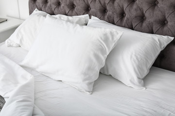 Soft white pillows on comfortable bed, closeup