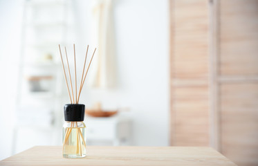Aromatic reed air freshener on table against blurred background