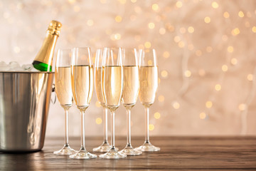 Glasses with champagne and bottle in bucket on table against blurred lights © New Africa