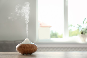 Modern aroma lamp on table against blurred background with space for text