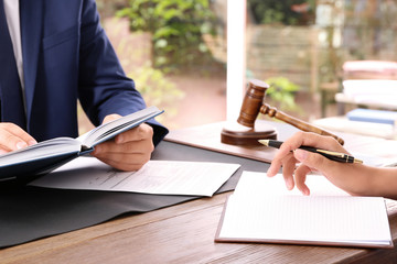 Lawyer working with client at table in office, focus on hands