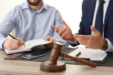 Gavel and blurred lawyer working with client on background