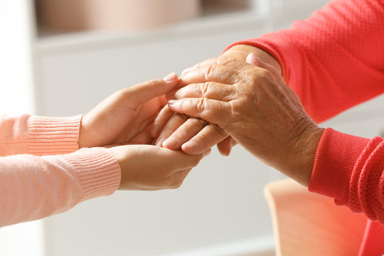 Helping hands on blurred background, closeup. Elderly care concept