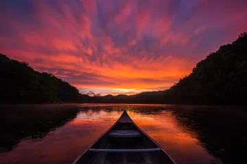 Foto op Plexiglas Humeurige zonsondergang over kalm meer met regendalingen op water van kano © aheflin