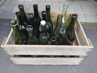 Alte staubige Flaschen in einer hölzernen Kiste.