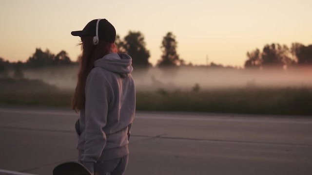 silhouette of a girl in headphones against the setting sun in nature. slow motion.