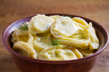 Dumplings, filled with cheese - vegetarian dish. Varenyky, vareniki, pierogi, pyrohy in a bowl on wooden table. horizontal