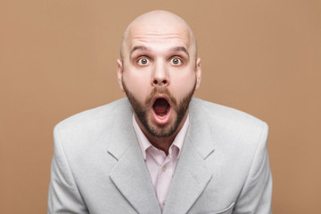 Pointing finger and amazed portrait of handsome middle aged businessman in classic light gray suit...