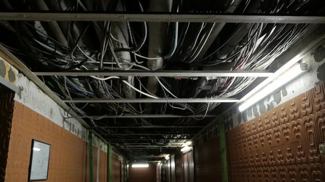 Basement floor of an building with many pipes and wires on ceiling without finishing.