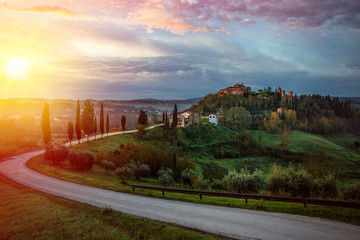 Obraz premium Sunset over the winding road with cypresses in Tuscany