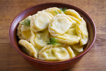 Dumplings, filled with cheese - vegetarian dish. Varenyky, vareniki, pierogi, pyrohy in a bowl on wooden table. horizontal