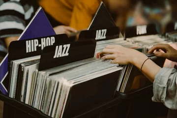 Foto op Plexiglas Muziekwinkel Vrouw kiest een vinylplaat in een muziekwinkel