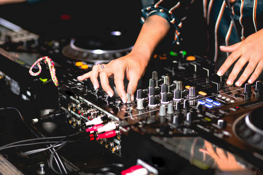 Young girl female shot party dj audio controlling mixing. Turntable High quality Sound mixing controller disc jockey hands of woman in night club party, Pro audio equipment on stage in nightclub . 