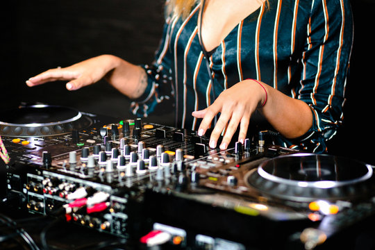 Young girl female shot party dj audio controlling mixing. Turntable High quality Sound mixing controller disc jockey hands of woman in night club party, Pro audio equipment on stage in nightclub . 
