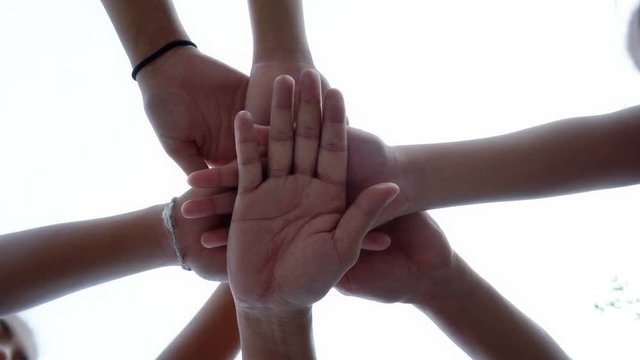 Successful team: many hands holding together on sky background
