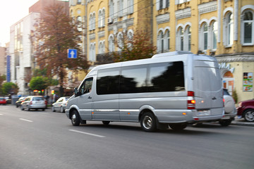 passenger bus van accelerating by city street - Powered by Adobe