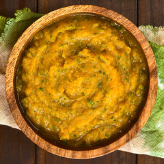 Pumpkin and parsley puree in wooden bowl, photographed overhead on dark wood with natural light (Selective Focus, Focus on the puree)