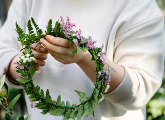 Woman is crafting the wreath of flowers. Beautiful nature floral head crown
